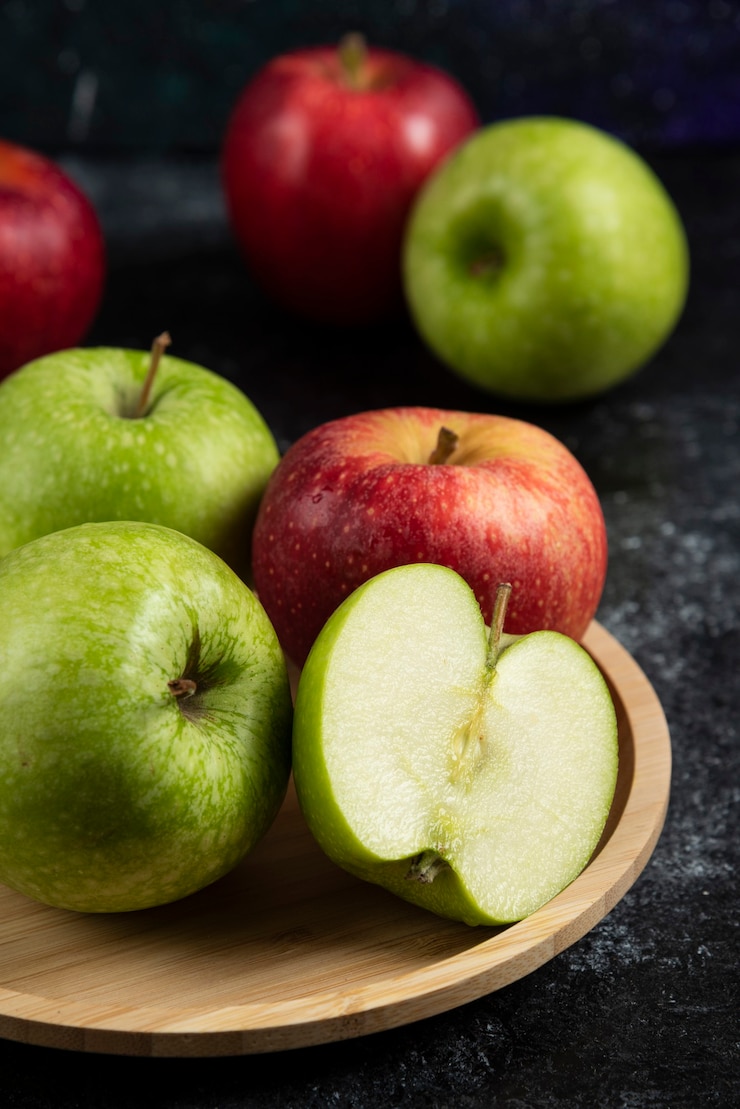 Kostenlose Foto ganze und geschnittene grüne und rote äpfel auf holzplatte.