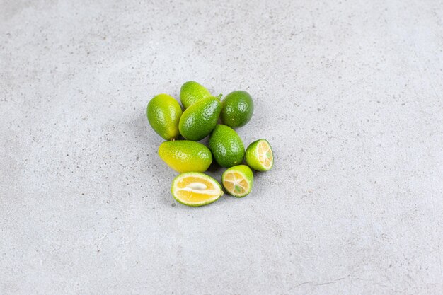 Ganze und geschnittene Kumquats auf Marmorhintergrund gelegt. Hochwertiges Foto