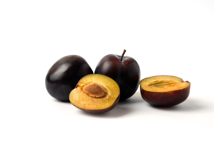 Kostenlose Foto ganze und geschnittene schwarze kirschpflaumen auf dem weißen tisch