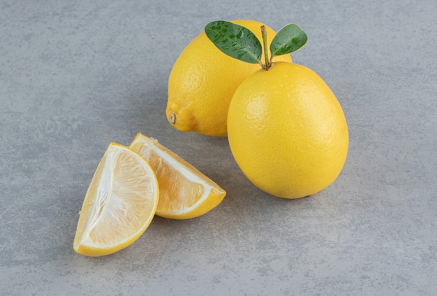 Ganze und in Scheiben geschnittene Zitronen auf Marmor