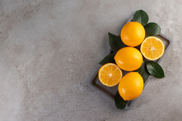 Ganze und in Scheiben geschnittene Zitronen mit Blättern an Bord.
