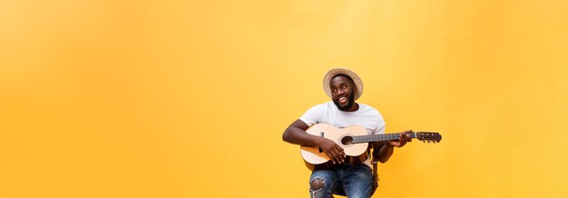 Ganzkörperfoto eines aufgeregten künstlerischen Mannes, der seine Gitarre spielt, isoliert auf gelbem Hintergrund