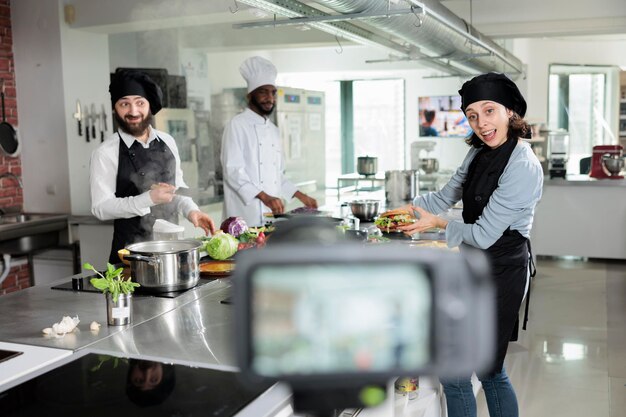 Gastronomieexperten in der professionellen Restaurantküche kochen köstliche Gourmetgerichte für den kulinarischen Schulkurs. Köche drehen ein Video über den Zubereitungsprozess von Speisen für eine gastronomische Fernsehsendung.