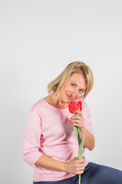 Gealterte Frau in rosafarbener Bluse mit Blume