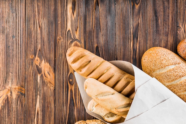 Kostenloses Foto gebackene baguettes eingewickelt im papier auf holztisch