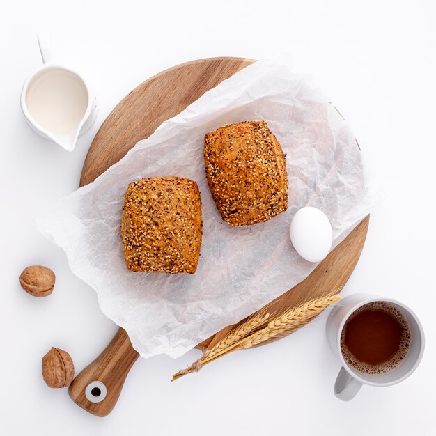 Gebackene Brötchen auf hölzernem Brett mit Tasse Kaffee