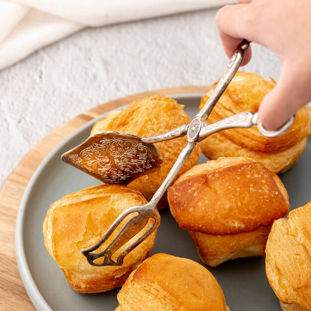 Gebackene Brötchen und Hand der hohen Ansicht der Nahaufnahme