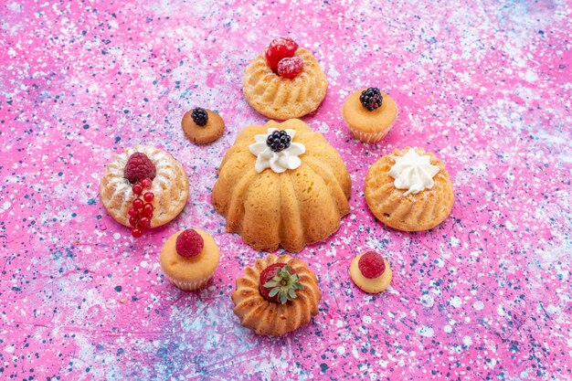 gebackene leckere Kuchen mit Sahne zusammen mit verschiedenen Beeren auf hellem Schreibtisch, Kuchen Keks Beeren süß backen Tee