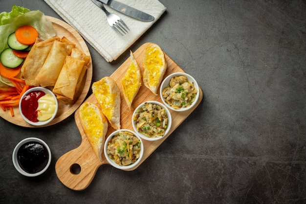 Gebackene Muschel mit Knoblauch und Butter, serviert mit Knoblauchbrot auf dunklem Hintergrund