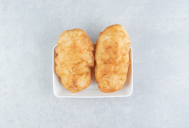 Gebackene Piroshki mit Kartoffeln in weißer Schüssel.