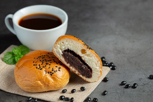 gebackene schwarze Bohnenpastenbrötchen auf braunem Stoff, serviert mit Kaffee