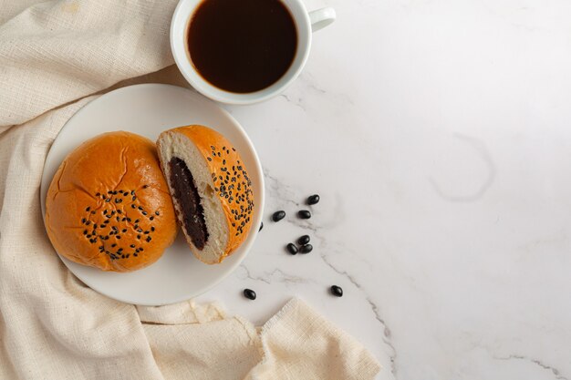 gebackene schwarze Bohnenpastenbrötchen auf weiße Schüssel mit Kaffee serviert