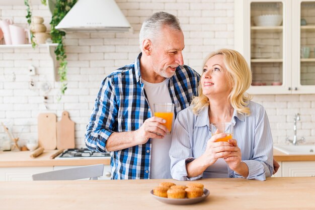 Gebackene selbst gemachte Muffins auf Tabelle vor reizenden lächelnden jungen Paaren in der Küche