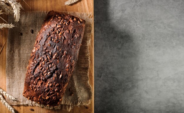 Gebackener Brotlaib auf einer Serviette, auf einem Schneidebrett, Draufsicht mit Kopienraum für Werbung oder Rezept. Natürlich fermentiertes Brot, gesundes Essen. Layout auf einem grauen Tisch