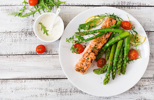 Gebackener Lachs, garniert mit Spargel und Tomaten mit Kräutern. Draufsicht