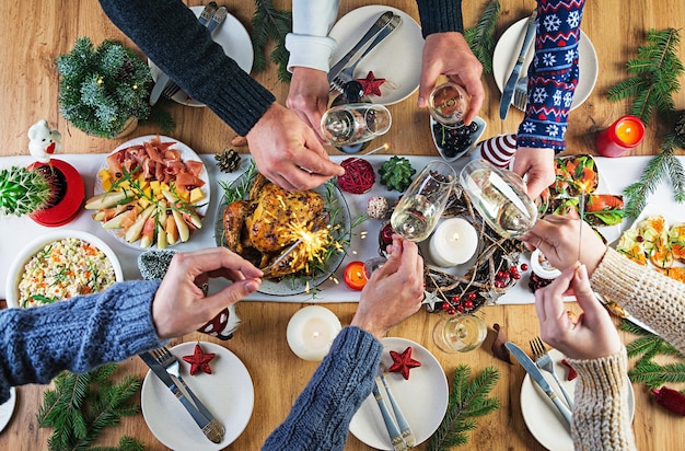 Gebackener Truthahn. Weihnachtsessen. Der Weihnachtstisch wird mit einem Truthahn serviert, der mit hellem Lametta und Kerzen dekoriert ist. Brathähnchen, Tisch. Familienessen. Draufsicht, Hände im Rahmen