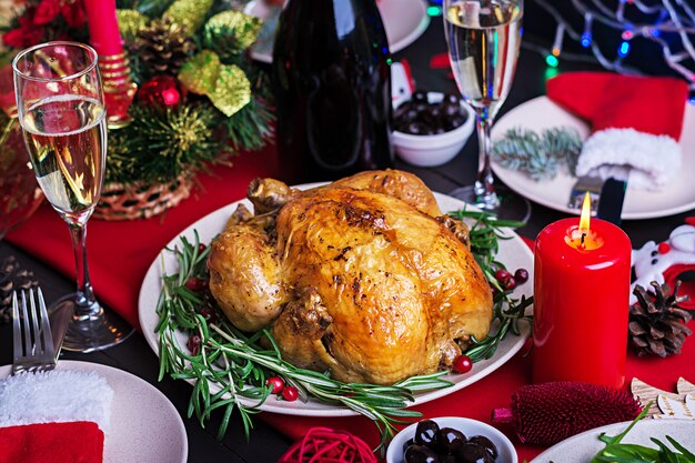 Gebackener Truthahn. Weihnachtsessen. Der Weihnachtstisch wird mit einem Truthahn serviert, der mit hellem Lametta und Kerzen dekoriert ist. Brathähnchen, Tisch. Familienessen.