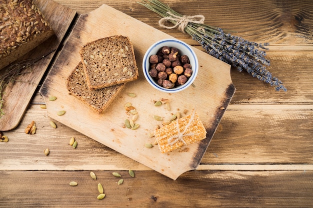 Gebackenes Brot und Energieriegel auf Schneidebrett über dem Tisch