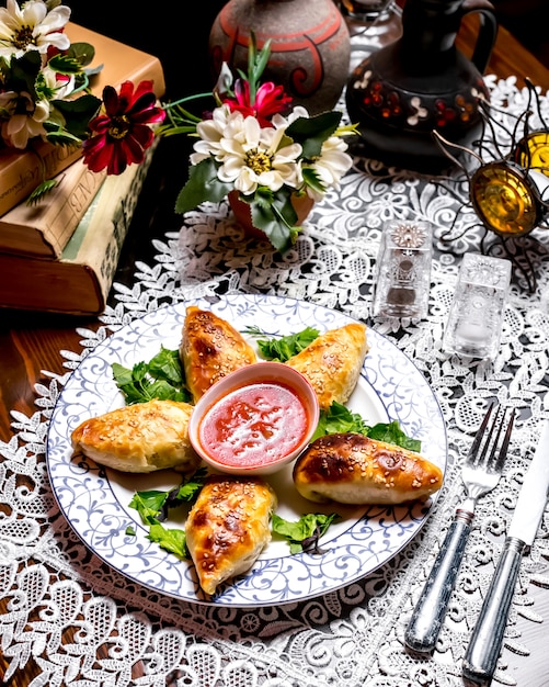 Kostenloses Foto gebackenes gefülltes gebäck mit sesamstreuseln, serviert mit tomatensauce