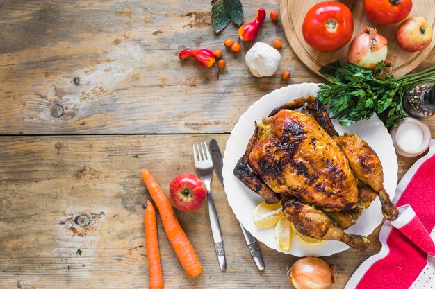 Gebackenes Huhn zwischen verschiedenem Gemüse, Löffel und Messer