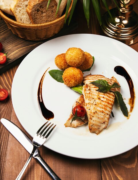 Gebackenes Lachsfilet mit Kartoffeln, Käseröllchen und Gemüsemischung.