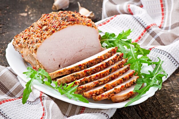 Gebackenes Schweinefleisch verziert mit Arugulablättern