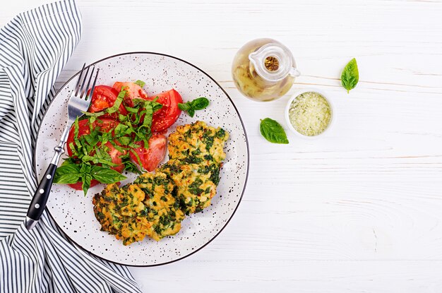 Gebackenes Steak gehacktes Hähnchenfilet mit Spinat und einer Beilage Tomatensalat. Europäische Küche. Diätetisches Essen. Draufsicht