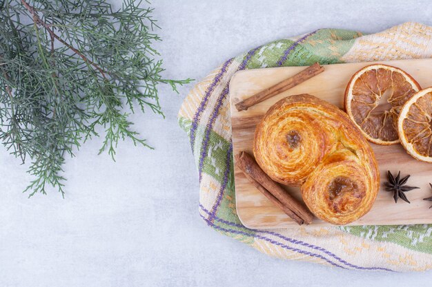 Gebäck mit Zimtstangen, Nelken und Orangen auf Holzbrett.