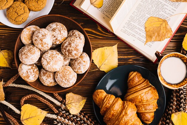 Gebäck und Milch nahe Schal und Buch