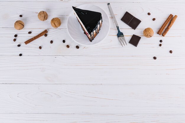 Gebäck; Walnüsse; Zimt; Kaffeebohnen; Gabel und Schokoriegel über weißem Hintergrund aus Holz