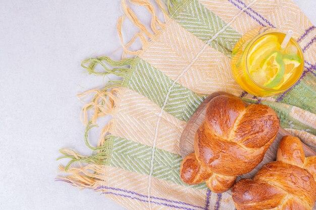 Gebäckbrötchen auf einem Holzbrett mit einem Glas Limonade