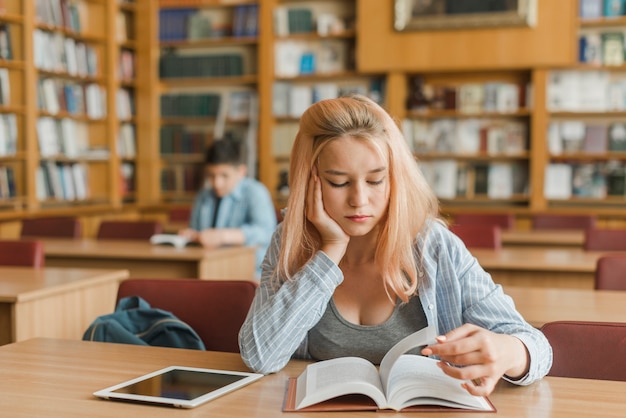 Kostenloses Foto gebohrter jugendlicher, der in der bibliothek studiert