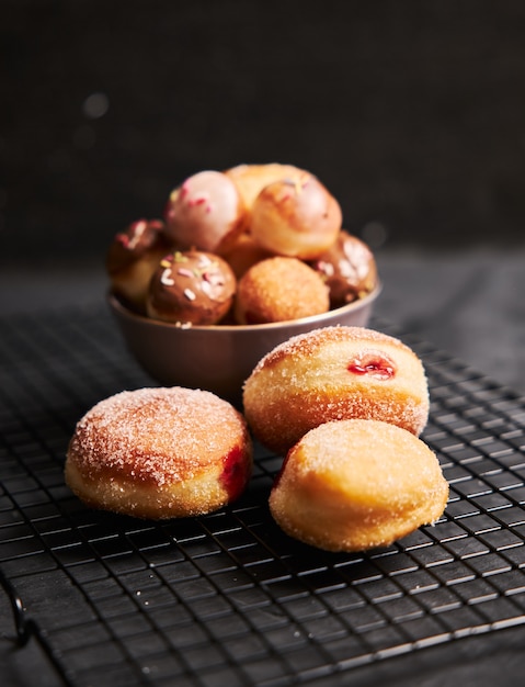 Gebratene donuts mit zucker und sahne auf einem schwarzen tisch