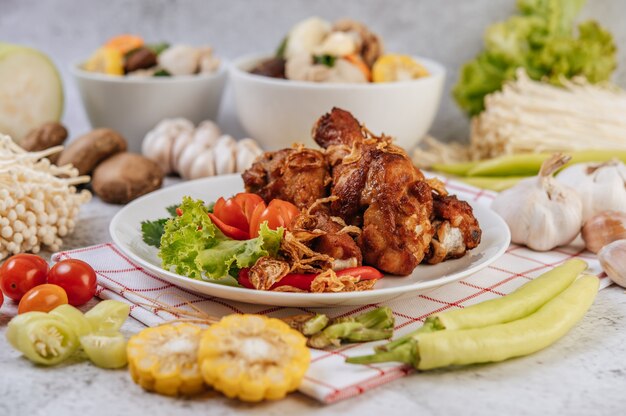 Gebratene Hähnchenkeule mit Tomate, Chili, gebratenen Zwiebeln, Salat, Mais und Nadelpilz.