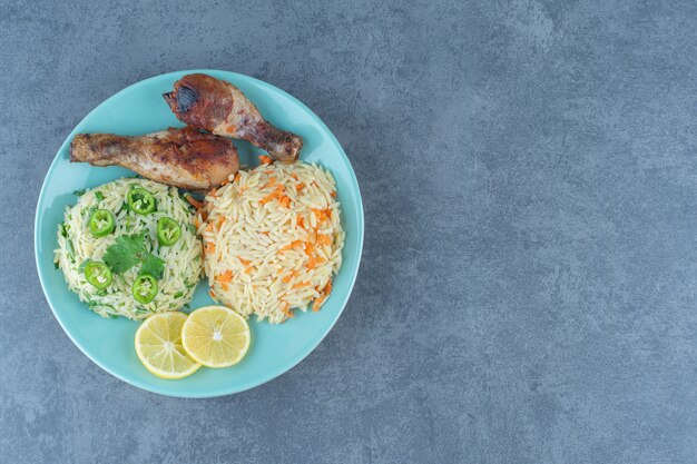 Gebratene Hühnerbeine und Reis auf blauem Teller.