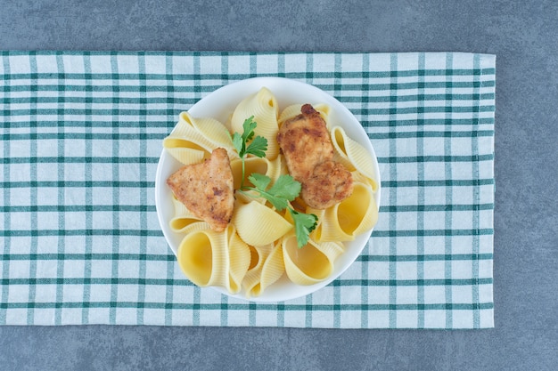 Gebratene Hühnernuggets und gekochte Nudeln in weißer Schüssel.