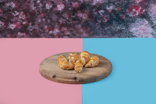 Gebratene kaukasische mutaki Kekse auf einem Holzbrett auf rosa blauem Tisch.