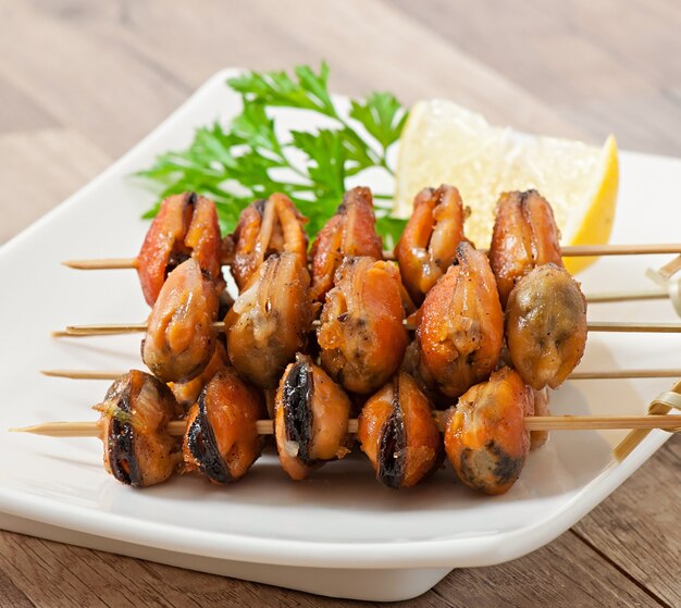 Gebratene Miesmuscheln mit Zwiebeln am Spieß, garniert mit grünen Bohnen und Paprika