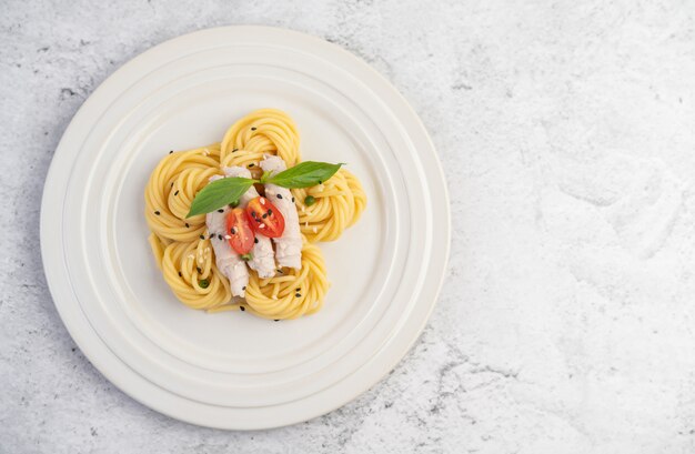 Gebratene Spaghetti und Schweinefleisch, wunderschön in einem weißen Teller angeordnet.