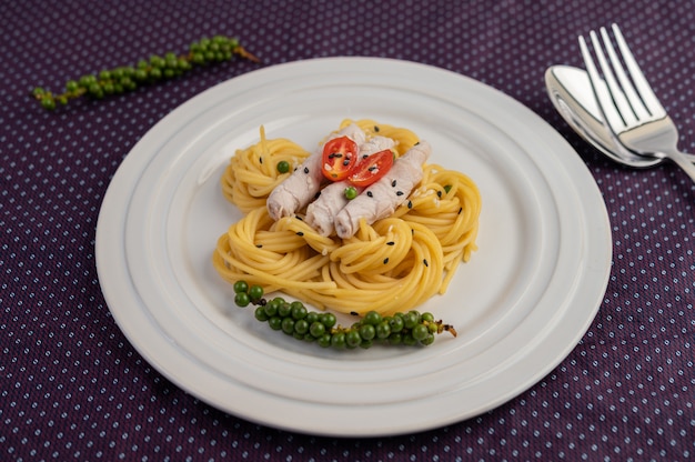 Gebratene Spaghetti und Schweinefleisch, wunderschön in einem weißen Teller angeordnet.