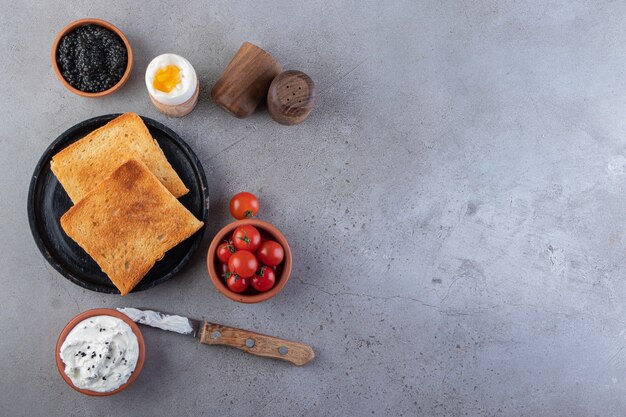 Gebratene Toasts mit Butter und roten frischen Kirschtomaten auf Hintergrund gelegt.