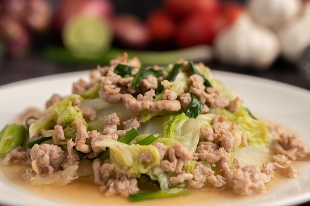 Gebratenen Chinakohl mit gehacktem Schweinefleisch in weißer Schüssel umrühren.