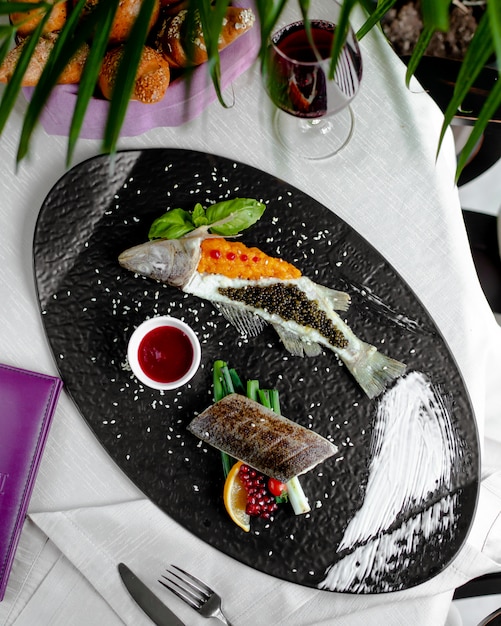 Gebratener Fisch mit rotem und schwarzem Kaviar dekoriert und mit Sauce serviert