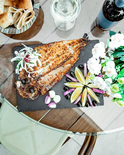 Gebratener Fisch mit Zitronenscheiben und Knoblauch