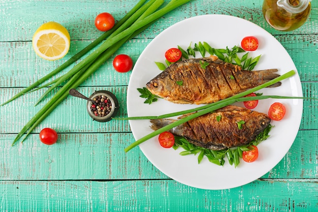 Gebratener Fischkarpfen und frischer Gemüsesalat auf Holztisch. Flach liegen. Draufsicht