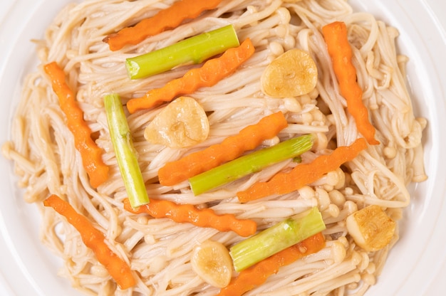 Gebratener goldener nadelpilz in einem weißen teller mit knoblauch