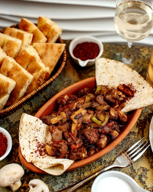 Kostenloses Foto gebratenes fleisch mit pilzen und korb mit brot