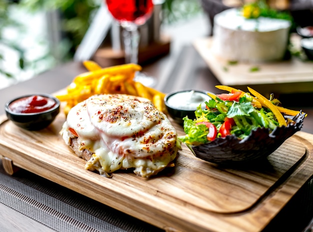 Gebratenes Hähnchenbrustkäse Tomaten Pommes Frites Ketchup und grüner Salat Seitenansicht jpg