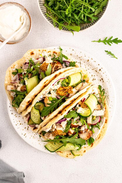 Gebratenes Hühnchen, Rucola, Gurken, Rettich, rote Zwiebeln und Weizen-Tortilla-Sauce zum Mittagessen, köstliche mexikanische Burritos oder Tacos, vertikales Rezept