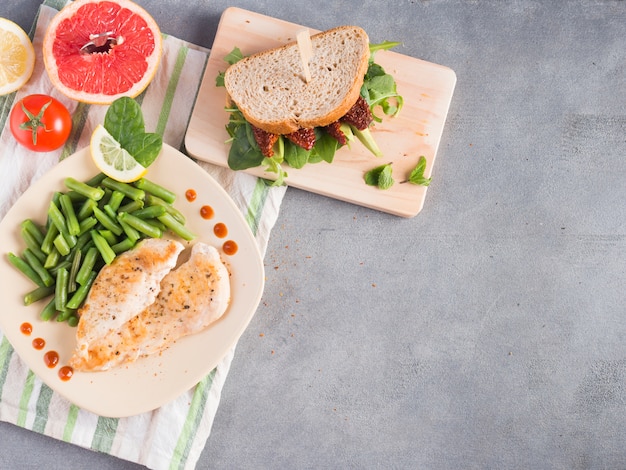 Kostenloses Foto gebratenes huhn mit grünen bohnen und sandwich auf dem tisch